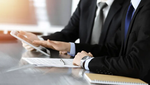 Businessman using tablet computer and work together with his colleague in sunny modern office, close-up. Unknown business people at meeting. Teamwork and partnership concept