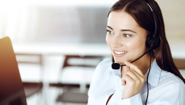 Представниця служби клієнтки Brunette за допомогою навушників і консалтингу клієнтів в Інтернеті. Центр виклику — стокове фото