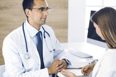 Doktor ve hasta klinikteki masada otururken bir şey tartışıyorlar. Tıp kavramı ve klinikte rahat hizmet