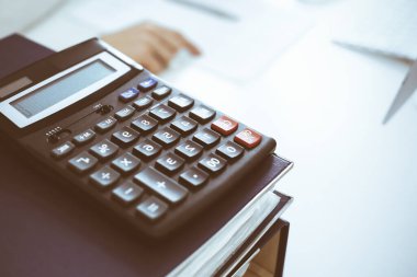 Hesap makinesi ve kağıtlar iş kadını ya da ofisteki büroda çalışan muhasebeci tarafından incelenmeyi bekliyor. İç Denetim ve vergi kavramı