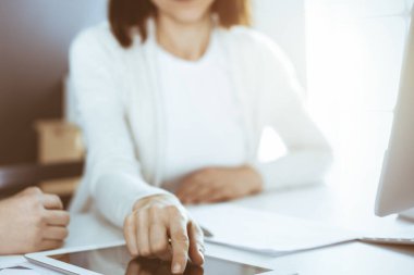 İş kadını, bayan meslektaşına sunum yaparken tablet bilgisayar ekranını işaret ediyor. Ofisteki masada çalışan bir grup iş adamı. Takım çalışması konsepti