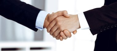 Modern bir ofiste dururken iş adamları kontrattan sonra el sıkışıyor. Takım çalışması ve el sıkışma kavramı