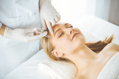 Güzellik doktoru sarışın kadın yüzüne şırıngayla güzellik prosedürü uyguluyor. Kozmetik tıp, güzellik enjeksiyonu konsepti