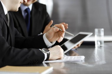 Bilinmeyen işadamları tablet bilgisayar kullanıyor ve modern ofisteki cam masada birlikte çalışıyorlar. Yakın plan. Takım çalışması ve ortaklık kavramı