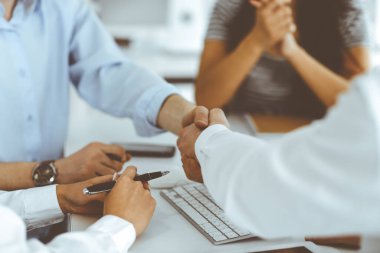 İki işadamı büroda otururken el sıkışıyorlar, yakın plan. Meslektaşların başarı toplantısını alkışlaması sona erdi. İş adamları konsepti