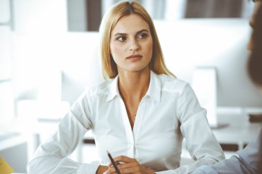 Bir grup iş adamı toplantıda soruları tartışıyor. Ofis görüşmelerinde iş arkadaşına gülümseyen sarışın iş kadınının vesikalığı. Şirket işgalinde takım çalışması ve işbirliği