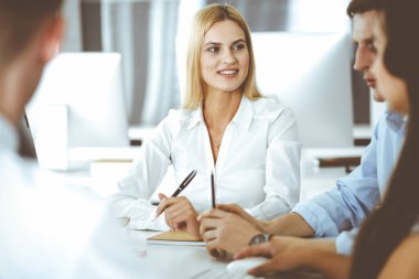 Bir grup iş adamı toplantıda soruları tartışıyor. Ofis görüşmelerinde iş arkadaşına gülümseyen sarışın iş kadınının vesikalığı. Şirket işgalinde takım çalışması ve işbirliği