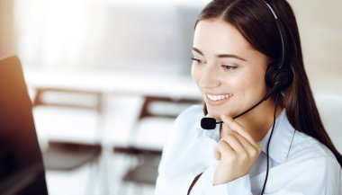 Esmer kadın müşteri hizmetleri temsilcisi kulaklık ve danışman müşteriler kullanıyor. Çağrı merkezi