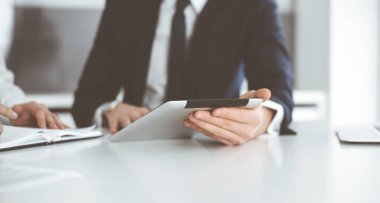 Bilinmeyen iş adamları modern ofiste tablet bilgisayar kullanıyorlar. İş adamı ya da erkek girişimci, çalışma masasında meslektaşıyla birlikte çalışıyor.