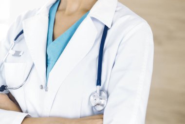 Klinikte kolları çapraz duran kimliği belirsiz kadın doktor, yakın plan. Tıp konsepti