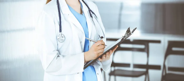 Bilinmeyen kadın doktor ya da stajyer öğrenci klinikte tıbbi geçmişi dolduruyor, yakın plan. İlaç ve sağlık hizmetleri kavramı