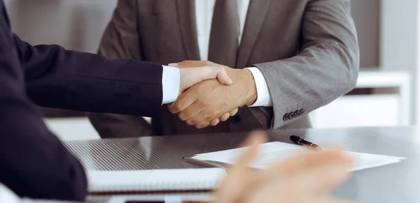 Unknown business people are shaking hands after contract signing in modern office, close-up. Handshake as successful negotiation ending