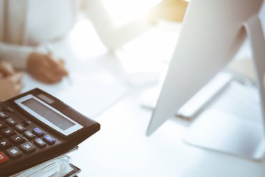 Hesap makinesi ve kağıtlar iş kadını ya da ofisteki büroda çalışan muhasebeci tarafından incelenmeyi bekliyor. İç Denetim ve vergi kavramı