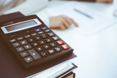 Hesap makinesi ve kağıtlar iş kadını ya da ofisteki büroda çalışan muhasebeci tarafından incelenmeyi bekliyor. İç Denetim ve vergi kavramı