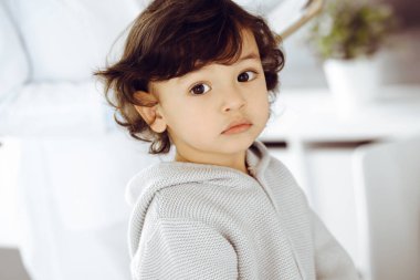 Kadın doktor, bir çocuk hastayı steteskopla muayene ediyor. Doktor randevusunda tatlı bir Arap bebek. Tıp konsepti