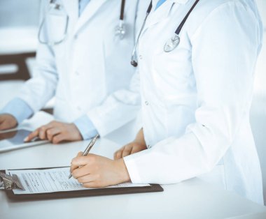 Klinik resepsiyonunda çalışan kimliği belirsiz iki kadın doktor, yakın plan. Sağlık ve tıptaki veriler