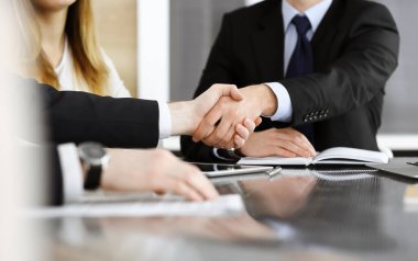 Bilinmeyen işadamları modern bir ofiste cam masanın üstünde el sıkışıyor. Toplantıda bilinmeyen iş adamları var. Takım çalışması, ortaklık ve el sıkışma kavramı