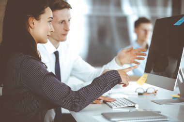 İş kadını ve erkek, modern ofiste bilgisayar kullanırken soruları tartışıyorlar. Takım çalışması, toplantı ve beyin fırtınası konsepti