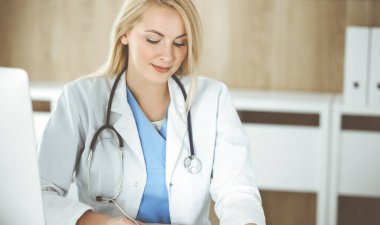 Hastanedeki ya da klinikteki masa başında oturan kadın doktor. Sarışın, neşeli doktor ilaç geçmişi formunu dolduruyor.