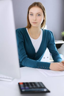 Muhasebeci mali durumu kontrol ediyor ya da vergi formları için hesap makinesi geliri ile sayıyor, eller yakın çekim. Ofisteki masada oturan ve çalışan bir iş kadını. Denetim kavramı