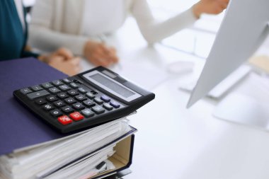 Hesap makinesi ve kağıtlar iş kadını ya da ofisteki büroda çalışan muhasebeci tarafından incelenmeyi bekliyor. İç Denetim ve vergi kavramı