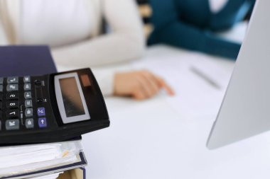 Hesap makinesi ve kağıtlar iş kadını ya da ofisteki büroda çalışan muhasebeci tarafından incelenmeyi bekliyor. İç Denetim ve vergi kavramı