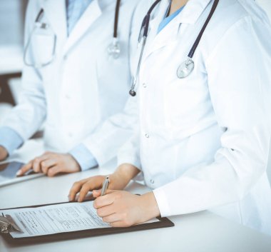 Klinik resepsiyonunda çalışan kimliği belirsiz iki kadın doktor, yakın plan. Sağlık ve tıptaki veriler