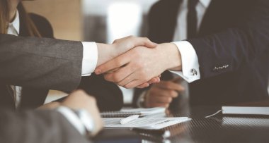 Bilinmeyen işadamı, modern ofiste iş arkadaşı ya da ortağıyla el sıkışıyor. Toplantıda iş adamları grubu