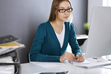 Muhasebeci mali durumu kontrol ediyor ya da vergi formları için hesap makinesi geliri ile sayıyor, eller yakın çekim. Ofisteki masada oturan ve çalışan bir iş kadını. Denetim kavramı