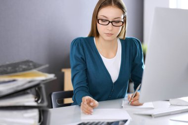 Muhasebeci mali durumu kontrol ediyor ya da vergi formları için hesap makinesi geliri ile sayıyor, eller yakın çekim. Ofisteki masada oturan ve çalışan bir iş kadını. Denetim kavramı