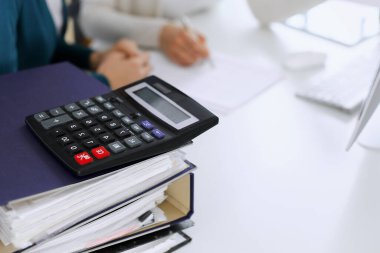 Hesap makinesi ve kağıtlar iş kadını ya da ofisteki büroda çalışan muhasebeci tarafından incelenmeyi bekliyor. İç Denetim ve vergi kavramı