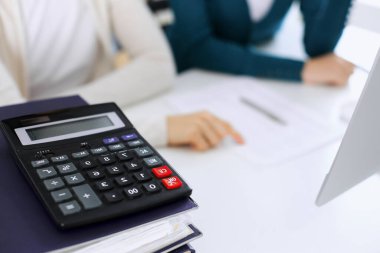 Hesap makinesi ve kağıtlar iş kadını ya da ofisteki büroda çalışan muhasebeci tarafından incelenmeyi bekliyor. İç Denetim ve vergi kavramı