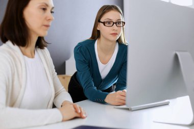 İş kadını, masa başında bilgisayarla otururken bayan meslektaşına sunum yapıyor. Ofiste çalışan bir grup iş adamı. Takım çalışması konsepti