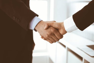 İş adamı ve kadın ofiste el sıkışıyor. İş hayatında başarı sembolü olarak el sıkışma kavramı