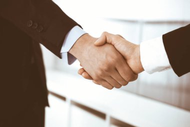 İş adamı ve kadın ofiste el sıkışıyor. İş hayatında başarı sembolü olarak el sıkışma kavramı