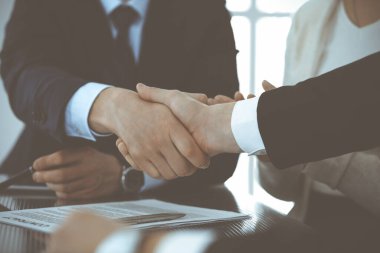 Modern ofiste iş adamları kontrat imzalandıktan sonra el sıkışıyor. Takım çalışması, ortaklık ve el sıkışma kavramı