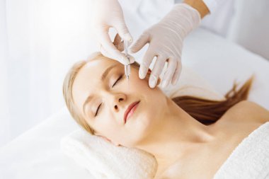 Güzellik doktoru, beyaz kadın yüzüne şırıngayla güzellik prosedürü uyguluyor. Kozmetik tıp ve cerrahi, güzellik enjeksiyonları konsepti