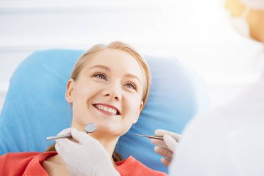 Mutlu gülümseyen kadın dişçi kliniğinde dişçi tarafından muayene ediliyor. Sağlıklı dişler ve ilaçlar, stomatoloji konsepti