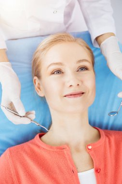 Mutlu gülümseyen kadın dişçi kliniğinde dişçi tarafından muayene ediliyor. Sağlıklı dişler ve ilaçlar, stomatoloji konsepti