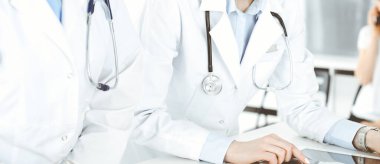 Arka planda hastası olan iki kadın doktor var. Resepsiyonda tıbbi belgeleri dolduran kadın doktorlar, yakın çekim. Tıptaki veriler