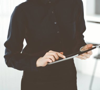 Bilinmeyen iş kadını ofiste dikilirken tablet bilgisayar kullanıyor, yakın plan. Ticarette veri