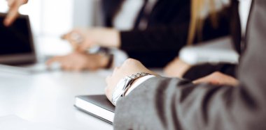 Meçhul iş adamları ve kadınlar modern ofiste oturuyorlar, çalışıyorlar ve sorularını tartışıyorlar.