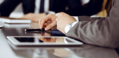 Bilinmeyen iş adamları ve kadınlar oturmuş, dizüstü bilgisayarlarını kullanıyorlar ve modern ofiste buluşmada soruları tartışıyorlar, yakın plan.