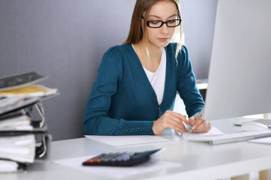 Muhasebeci mali durumu kontrol ediyor ya da vergi formları için hesap makinesi geliri ile sayıyor, eller yakın çekim. Ofisteki masada oturan ve çalışan bir iş kadını. Denetim kavramı