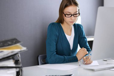 Muhasebeci mali durumu kontrol ediyor ya da vergi formları için hesap makinesi geliri ile sayıyor, eller yakın çekim. Ofisteki masada oturan ve çalışan bir iş kadını. Denetim kavramı