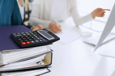 Hesap makinesi ve kağıtlar iş kadını ya da ofisteki büroda çalışan muhasebeci tarafından incelenmeyi bekliyor. İç Denetim ve vergi kavramı