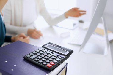 Hesap makinesi ve kağıtlar iş kadını ya da ofisteki büroda çalışan muhasebeci tarafından incelenmeyi bekliyor. İç Denetim ve vergi kavramı