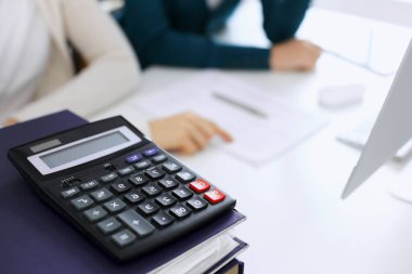 Hesap makinesi ve kağıtlar iş kadını ya da ofisteki büroda çalışan muhasebeci tarafından incelenmeyi bekliyor. İç Denetim ve vergi kavramı