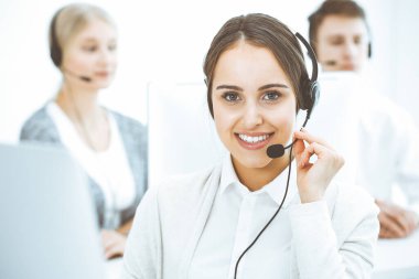 Merkezi ara. Çeşitli operatörler iş başında. Telepazarlama servisinin müşterileriyle iletişim kuran kulaklıklı güzel bir kadın. İş konsepti