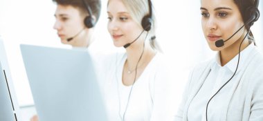 Merkezi ara. Çeşitli operatörler iş başında. Telepazarlama servisinin müşterileriyle iletişim kuran kulaklıklı güzel bir kadın. İş konsepti